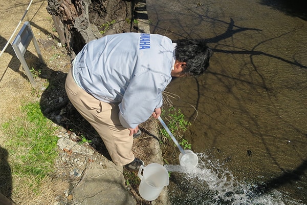 Mitarbeiter von Yamaha führen eine Wasserqualitätsprüfung an einem Fluss durch.