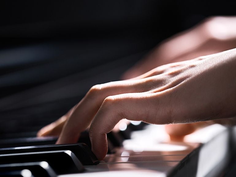 Close-up of a person's hand playing Yamaha Clavinova