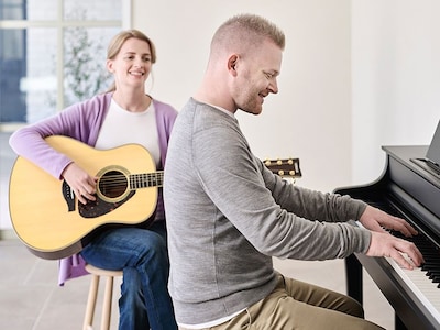 A person playing Yamaha Clavinova CLP-845B and a person playing guitar beside the person