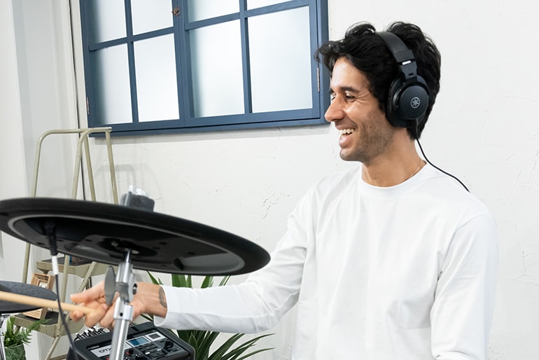 A man smiling while playing electronic drum kit