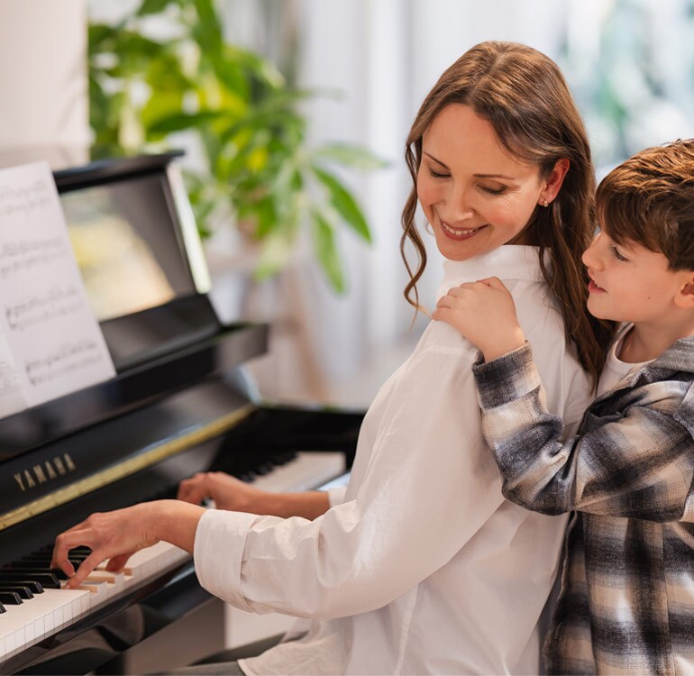 Eine Mutter und ihre Tochter spielen mit Freude auf einem Klavier der B-Serie